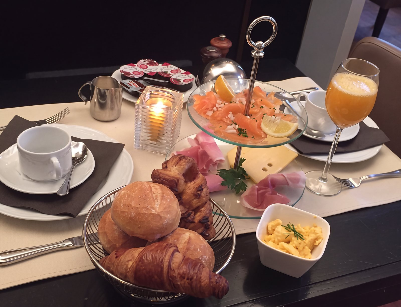 Ontbijt met croissants, zalm, ham en vers sinaasappelsap